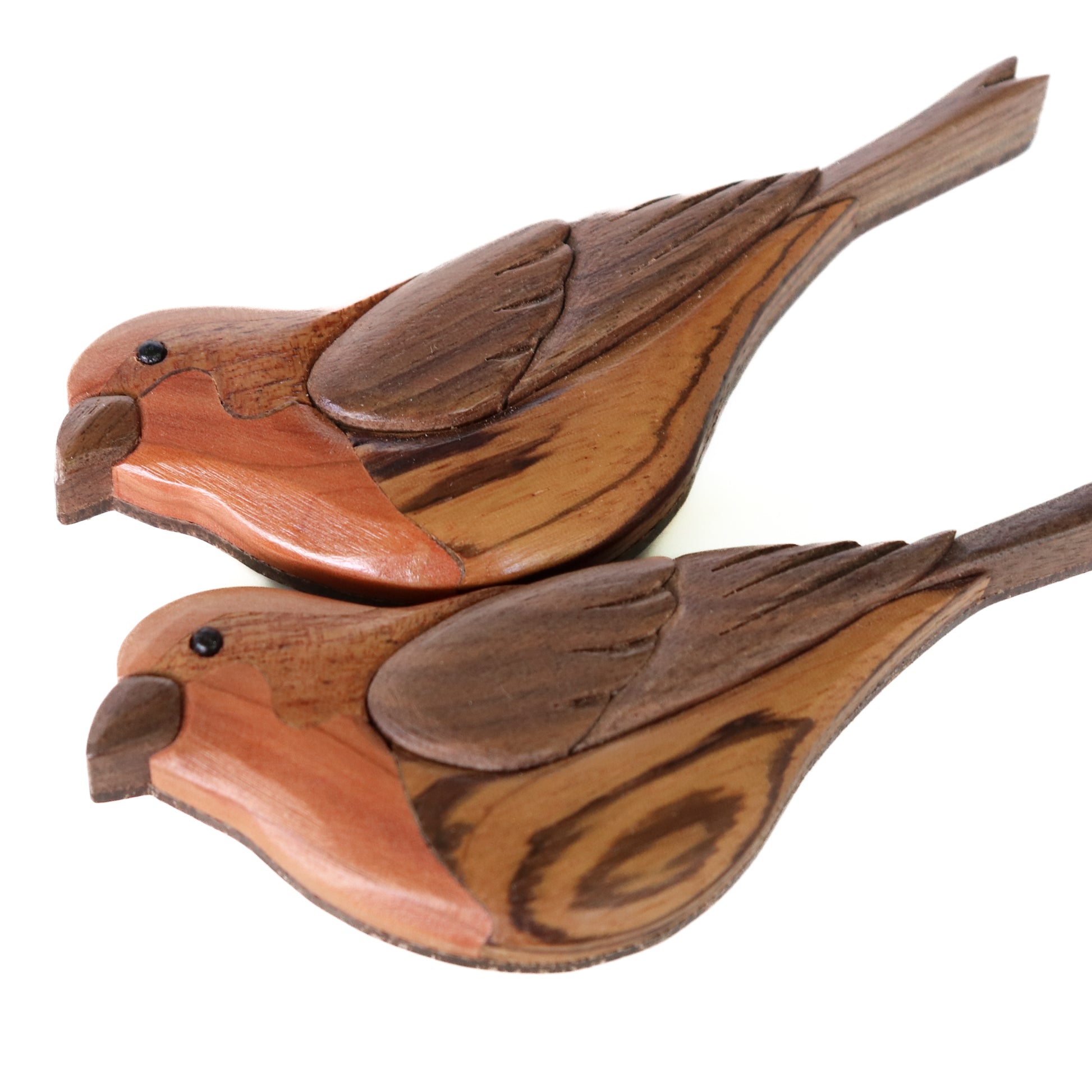 Two house finch intarsia art laying on their sides showing zebrawood wood grain on a white background.