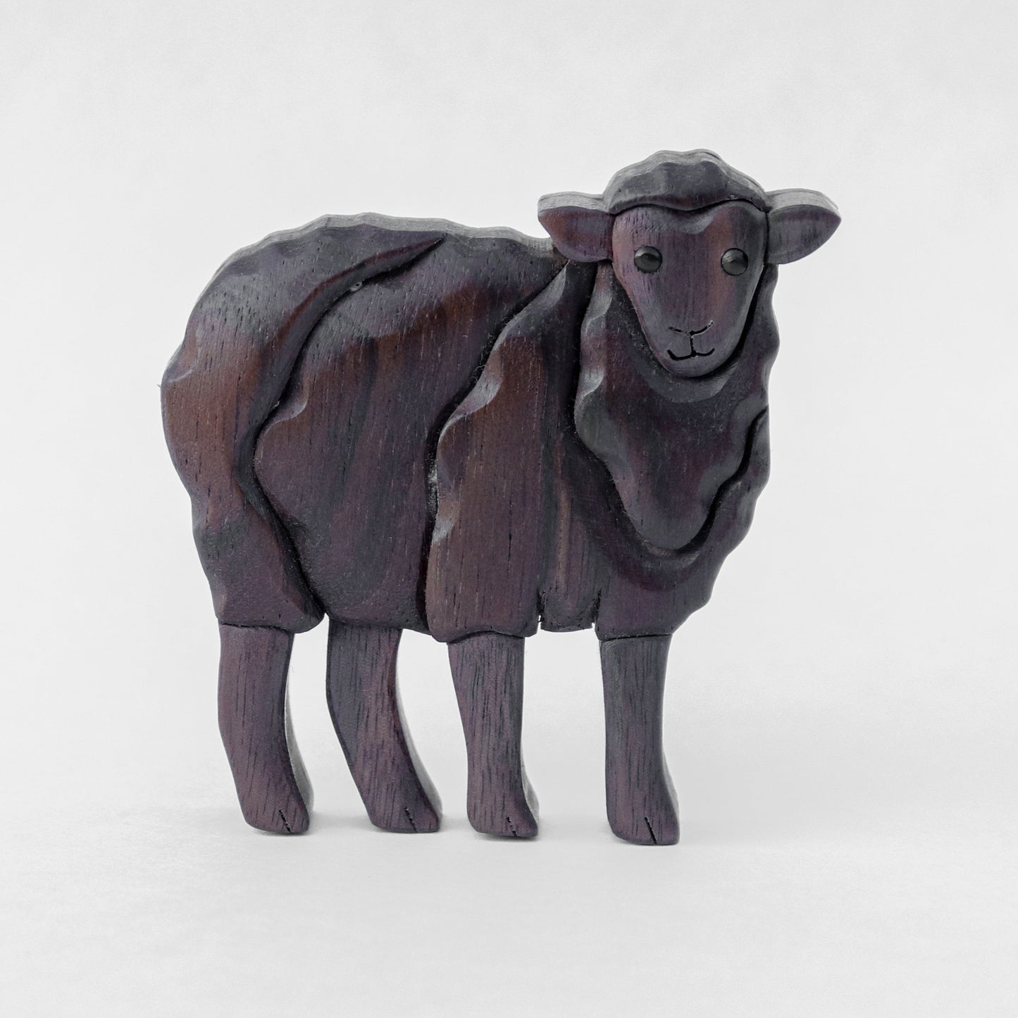 a black wooden sheep made from peruvian walnut and black walnut, standing with a white background