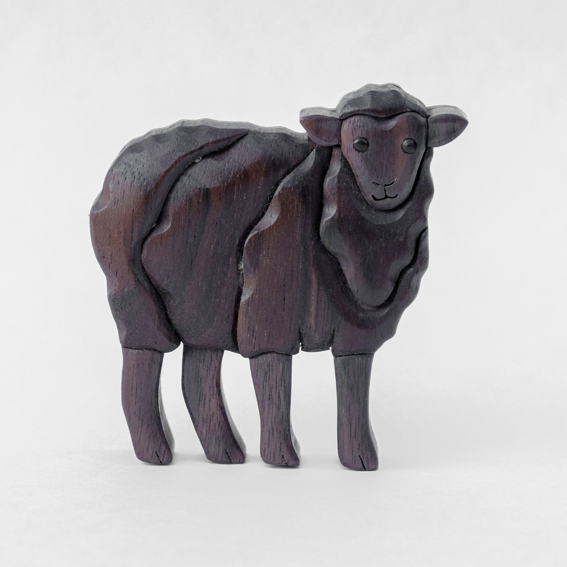 a black wooden sheep made from peruvian walnut and black walnut, standing with a white background