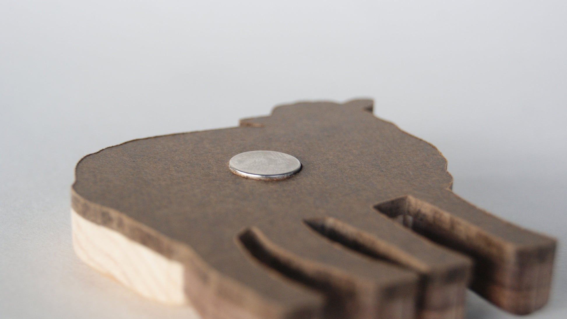 close up of a neodymium magnet inset in the hardboard back material of a wood intarsia carved white sheep.