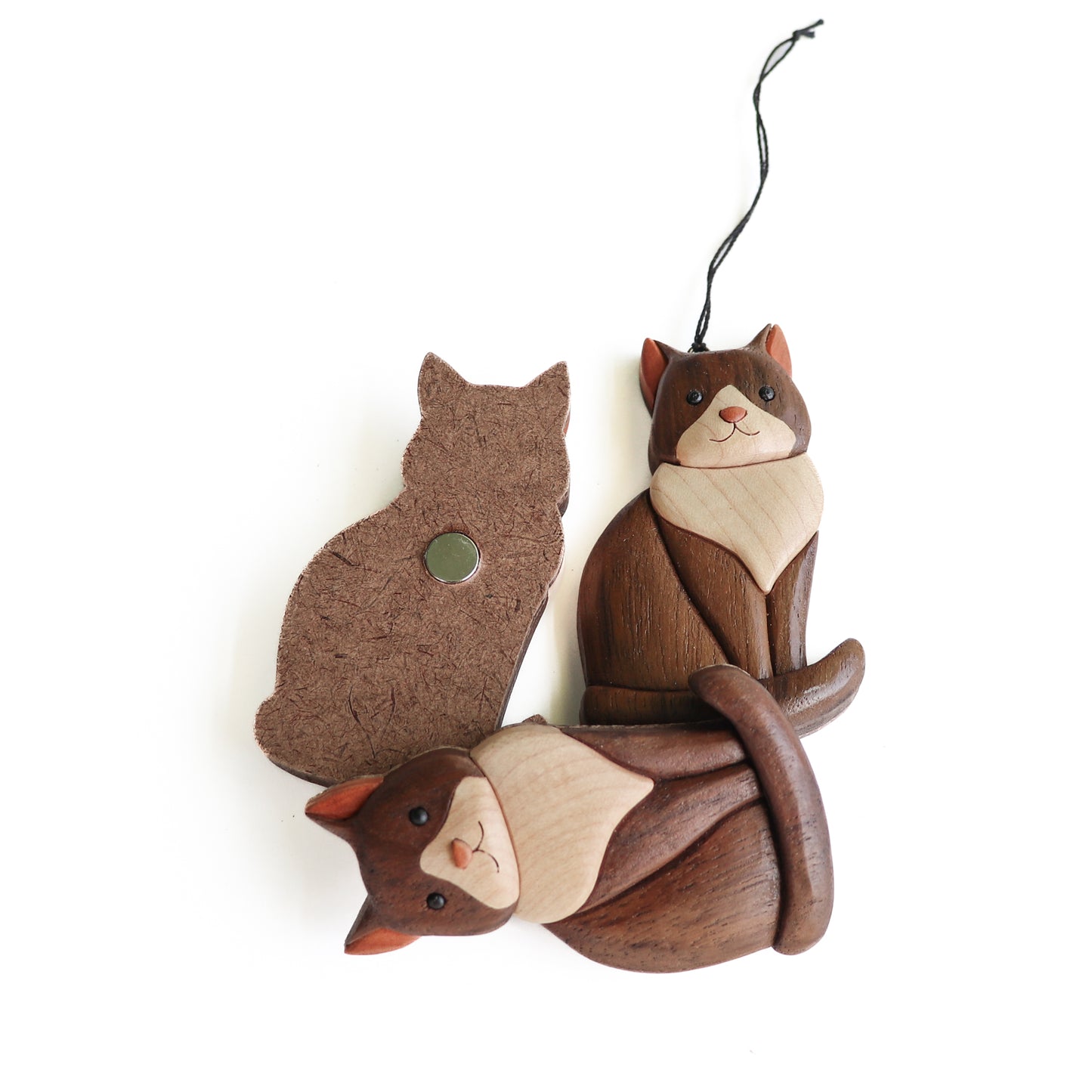 Three wooden tuxedo cat intarsia using the natural colors of the wood, one showing the backside using a neodymium  magnet, one with a screw eye and an a string and the other laying sideways