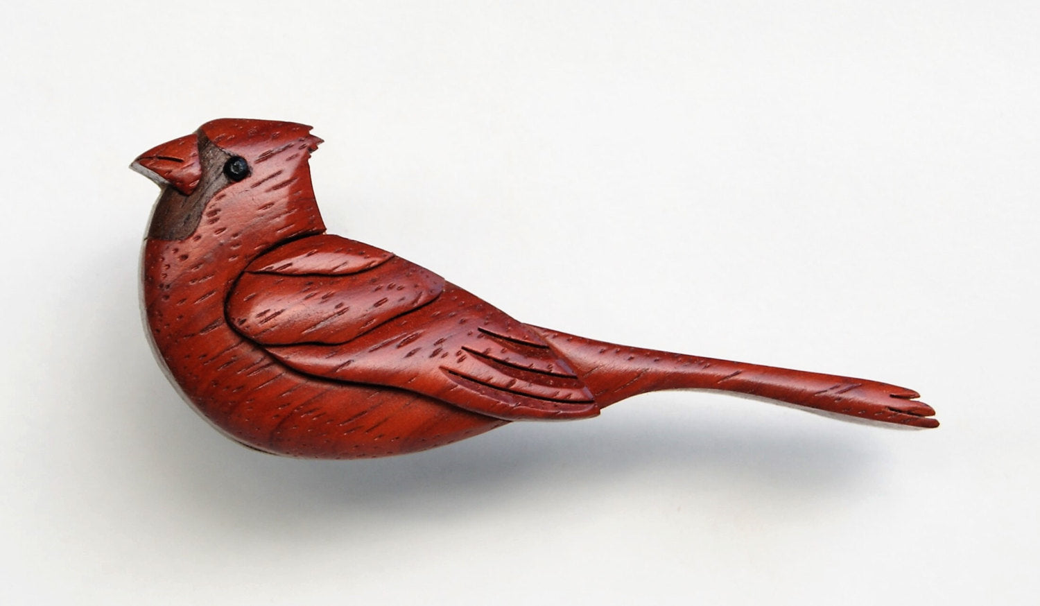 scroll saw cut wood intarsia of a cardinal using the natural colors of wood, showcasing the red woodgrain of padauk.
